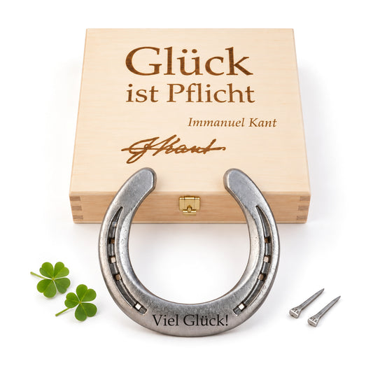 Glückshufeisen aus Stahl mit Gravur „Viel Glück!“ vor Holz-Geschenkbox mit Kant-Zitat „Glück ist Pflicht“, zwei Kleeblättern und zwei Hufnägeln