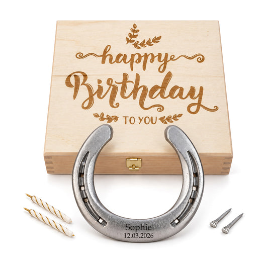 Glückshufeisen aus Stahl mit Gravur „Sophie 12.03.2026“ vor Holz-Geschenkbox mit Gravur „Happy Birthday to you“, zwei Geburtstagskerzen und zwei Hufnägeln
