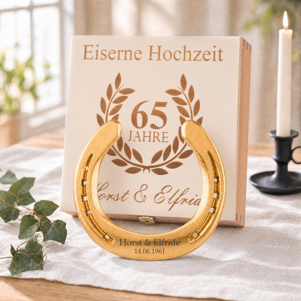 Vergoldetes Glückshufeisen (24 Karat) zur Eisernen Hochzeit mit Namensgravur vor der Holz-Geschenkbox, Deckel graviert mit Lorbeerkranz, 65 Jahre und Namen